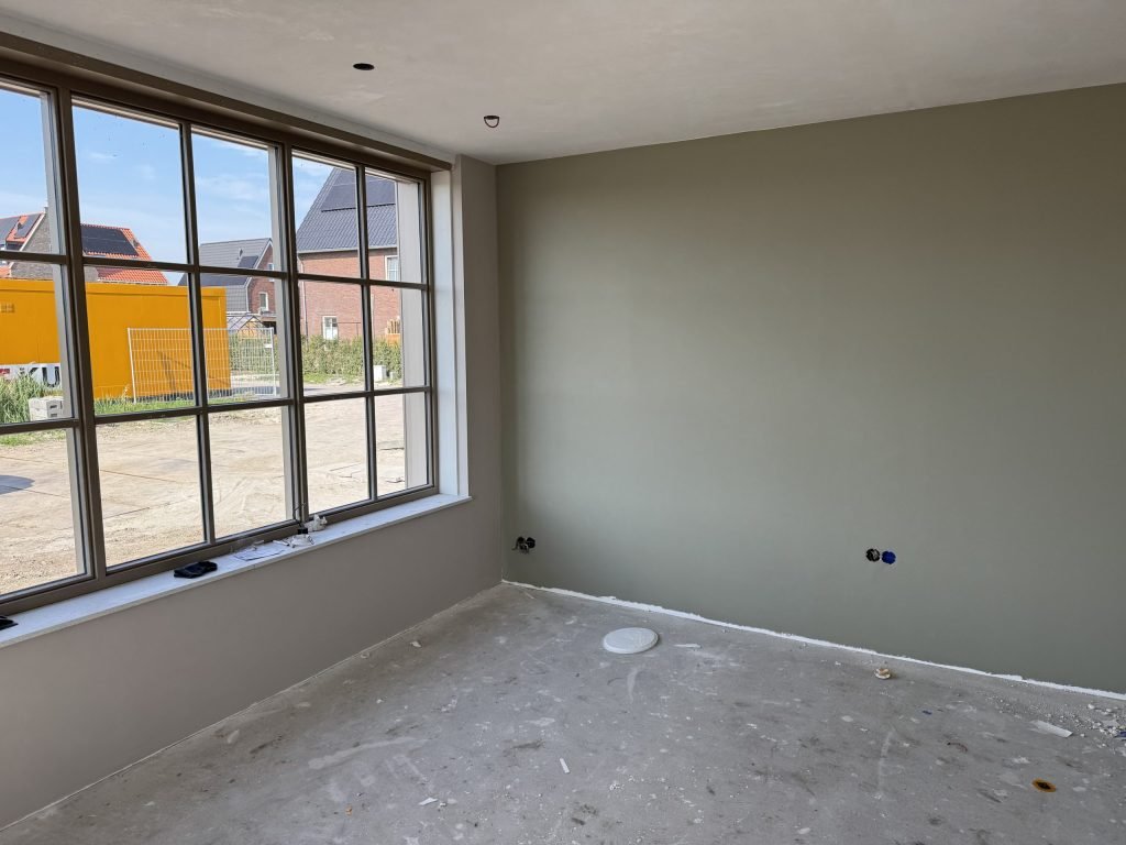 Kamer met een wand in een grijsgroene kleur naast een groot raam
