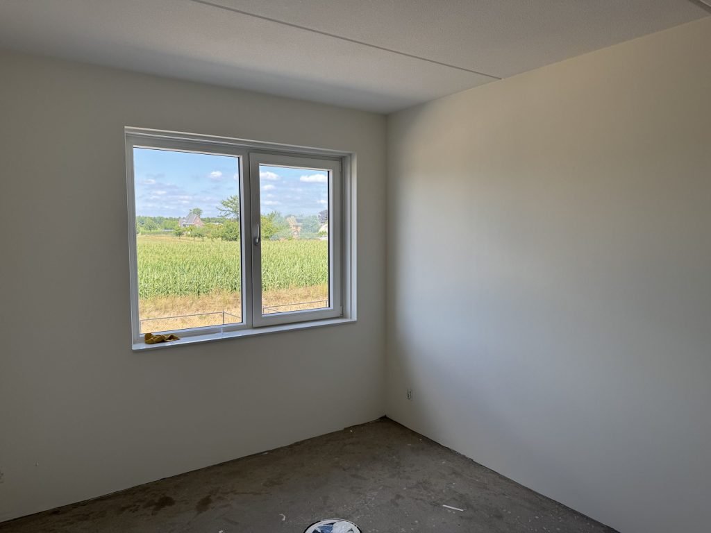 Lege kamer met lichte, gladde wanden en een raam, klaar om beoordeeld te worden